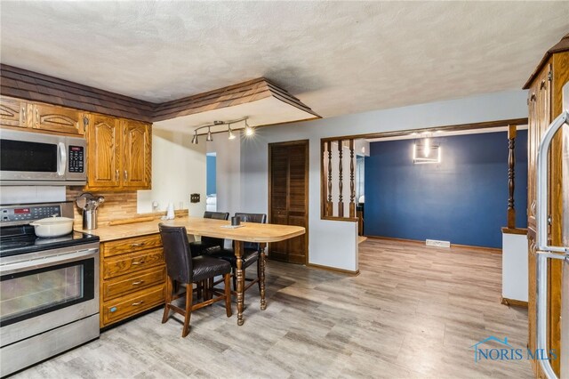 807 S Jefferson St, Pandora, OH 45877 - kitchen with appliances with stainless steel finishes, light countertops, brown cabinetry, track lighting, and light wood-type flooring