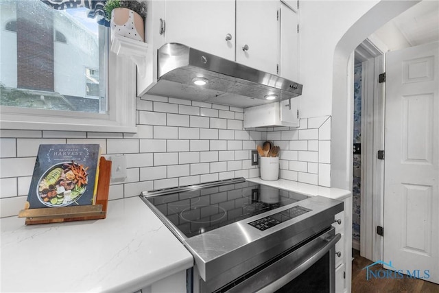 3418 Kirkwall Rd, Toledo, OH 43606 - kitchen with under cabinet range hood, stainless steel range with electric cooktop, arched walkways, white cabinets, and backsplash