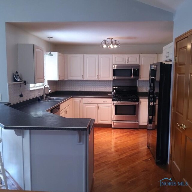 1623 Evan Dr, Defiance, OH 43512 - kitchen featuring stainless steel appliances, dark countertops, a peninsula, tasteful backsplash, and wood finished floors