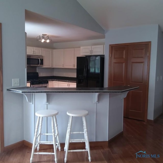 1623 Evan Dr, Defiance, OH 43512 - kitchen with stainless steel appliances, dark countertops, white cabinets, a kitchen bar, and lofted ceiling