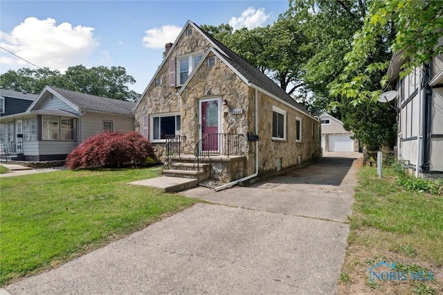 2624 Oak Grove Pl, Toledo, OH 43613 - english style home featuring stone siding, a front yard, an outbuilding, and a garage