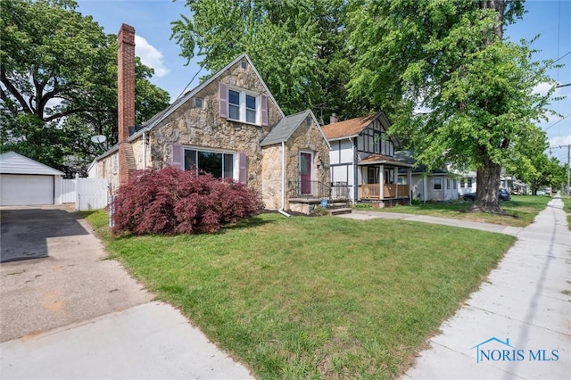 2624 Oak Grove Pl, Toledo, OH 43613 - english style home featuring stone siding, a garage, a front yard, an outdoor structure, and a chimney