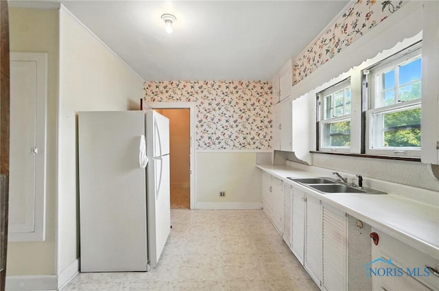 1452 Rollins Rd, Toledo, OH 43612 - kitchen featuring freestanding refrigerator, wallpapered walls, light flooring, light countertops, and white cabinetry
