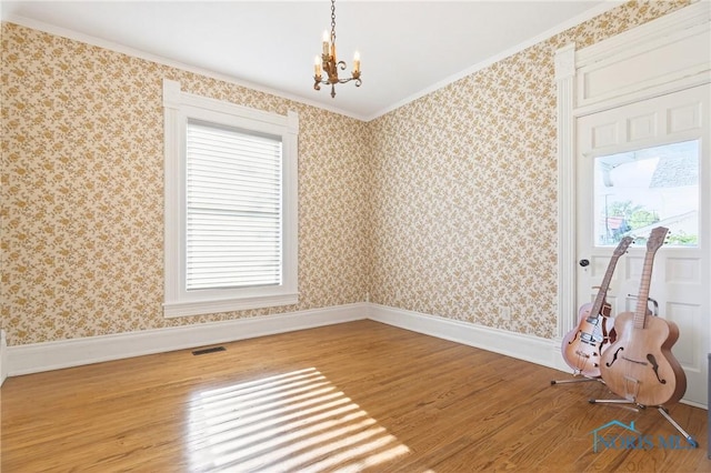 301 S High St, Pandora, OH 45877 - spare room featuring wood finished floors, a chandelier, and crown molding