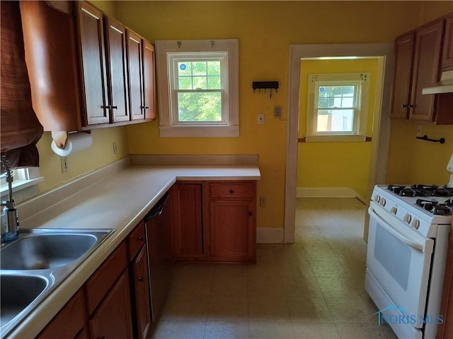 3906 Watson Ave, Toledo, OH 43612 - kitchen with gas range gas stove, stainless steel dishwasher, light countertops, range hood, and brown cabinetry