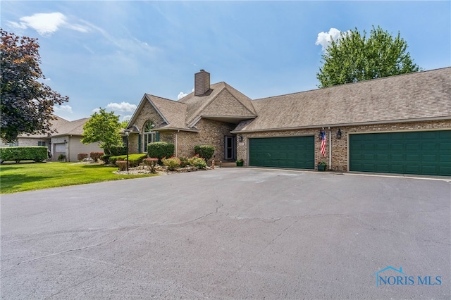 625 W Lake Ct Unit U5, Findlay, OH 45840 - view of front facade featuring asphalt driveway, a chimney, a garage, a front lawn, and brick siding