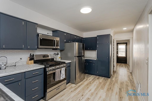 3947 Burnham Ave, Toledo, OH 43612 - kitchen featuring stainless steel appliances, light wood-style flooring, tasteful backsplash, and light stone counters