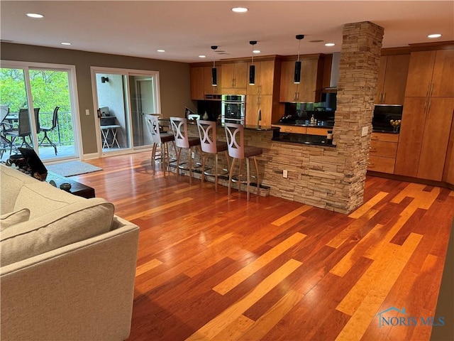 5831 Monroe St Unit 403, Sylvania, OH 43560 - kitchen featuring stainless steel double oven, light wood-type flooring, brown cabinets, recessed lighting, and decorative light fixtures