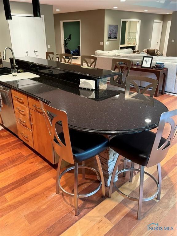 5831 Monroe St Unit 403, Sylvania, OH 43560 - kitchen featuring brown cabinetry, light wood finished floors, recessed lighting, dishwasher, and dark stone counters