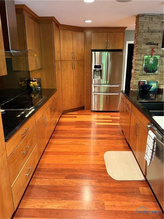 5831 Monroe St Unit 403, Sylvania, OH 43560 - kitchen with appliances with stainless steel finishes, wall chimney range hood, light wood-style floors, brown cabinets, and recessed lighting