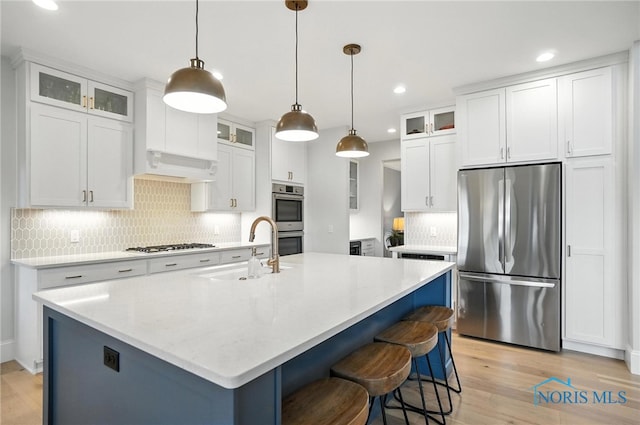 4214 Thornbury Ct, Perrysburg, OH 43551 - kitchen with stainless steel appliances, light wood-style floors, backsplash, premium range hood, and a center island with sink