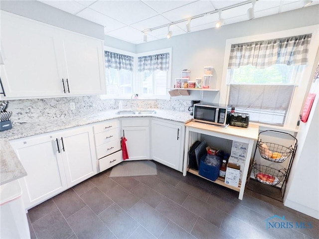 1925 Harlan Rd, Toledo, OH 43615 - kitchen with rail lighting, stainless steel microwave, white cabinets, light stone countertops, and dark tile patterned floors