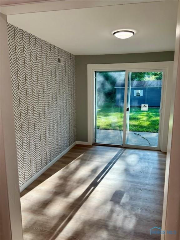 1948 Sudbury Dr, Holland, OH 43528 - empty room featuring an accent wall, wallpapered walls, and wood finished floors