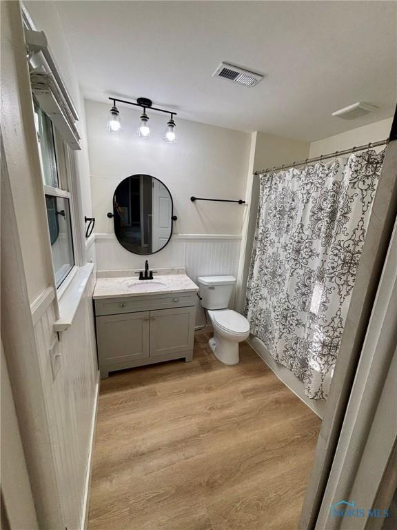 1948 Sudbury Dr, Holland, OH 43528 - bathroom with vanity, wood finished floors, wainscoting, and a shower with shower curtain