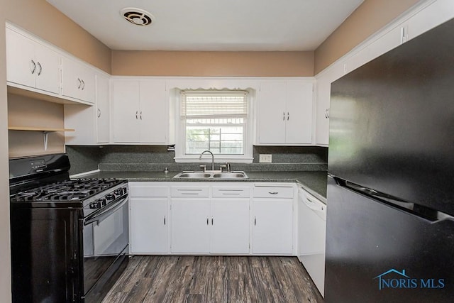 1831 Evansdale Ave, Toledo, OH 43607 - kitchen with freestanding refrigerator, black range with gas cooktop, dark countertops, dark wood-style flooring, and white cabinetry