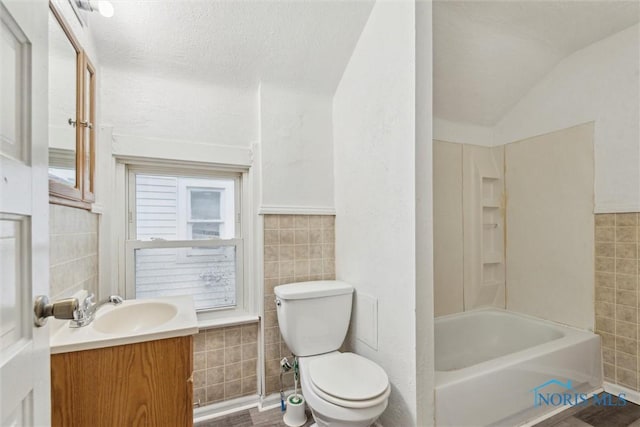 436 Danberry St, Toledo, OH 43609 - bathroom with tile walls, vanity, lofted ceiling, and shower / bath combination