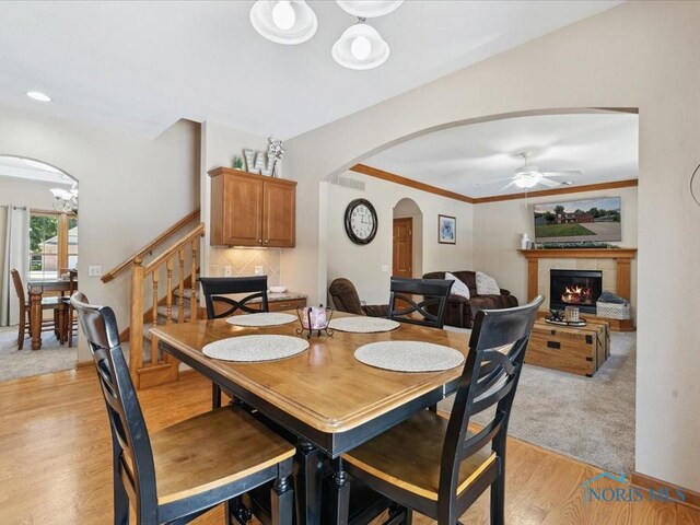 646 Whisperlake Rd, Holland, OH 43528 - dining room with arched walkways, light wood-type flooring, a fireplace, ceiling fan, and stairs
