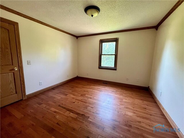 107 N Maple St, Payne, OH 45880 - spare room featuring crown molding, hardwood / wood-style flooring, and a textured ceiling