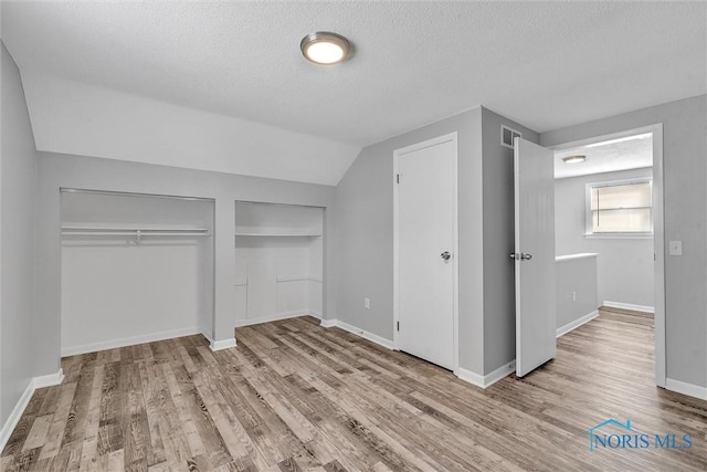 1845 Newport Ave, Toledo, OH 43613 - unfurnished bedroom featuring wood finished floors, a textured ceiling, two closets, and lofted ceiling