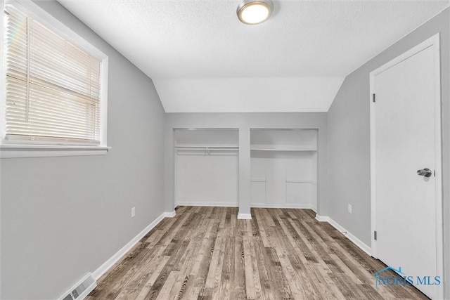 1845 Newport Ave, Toledo, OH 43613 - unfurnished bedroom with a textured ceiling, wood finished floors, lofted ceiling, and multiple closets