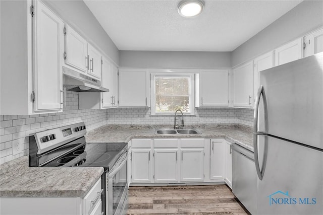 1845 Newport Ave, Toledo, OH 43613 - kitchen with stainless steel appliances, under cabinet range hood, white cabinetry, light countertops, and light wood-type flooring