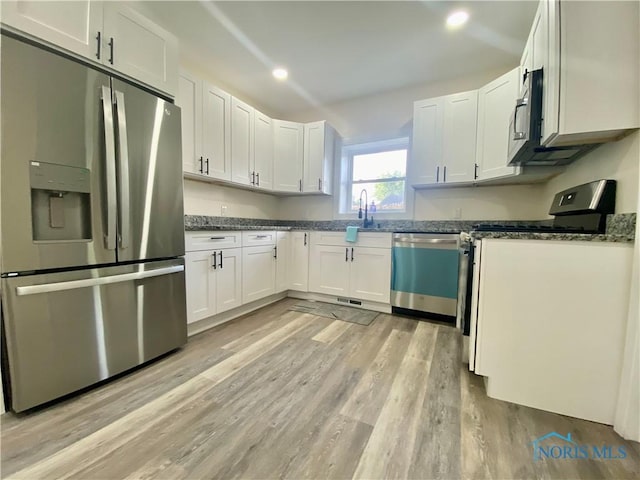 5240 Rambo Ln, Toledo, OH 43623 - kitchen with appliances with stainless steel finishes, light wood-type flooring, white cabinets, dark stone counters, and recessed lighting