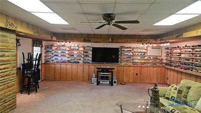 49 N Norden Rd, Oregon, OH 43616 - living room with light colored carpet, ceiling fan, a wall unit AC, wooden walls, and a drop ceiling