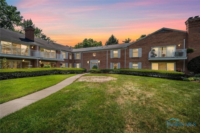 5679 Monroe St Unit 118, Sylvania, OH 43560 - view of front of home with a lawn, a balcony, brick siding, and a chimney