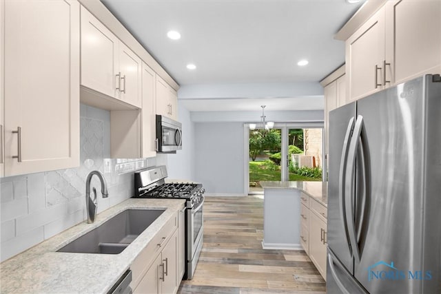 5679 Monroe St Unit 118, Sylvania, OH 43560 - kitchen featuring appliances with stainless steel finishes, light wood-style floors, recessed lighting, tasteful backsplash, and light stone countertops