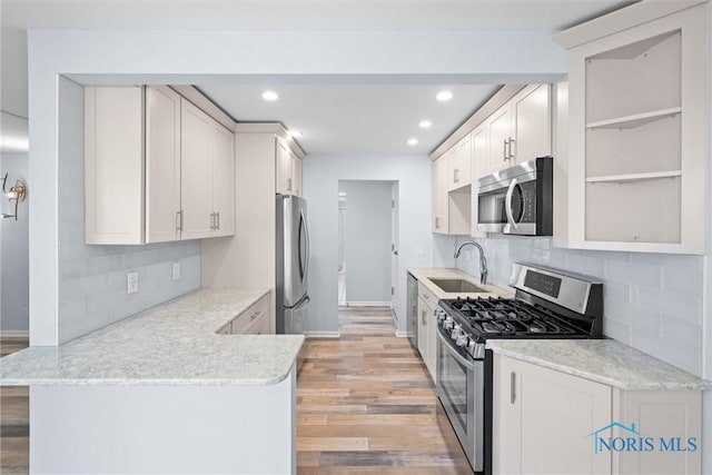 5679 Monroe St Unit 118, Sylvania, OH 43560 - kitchen featuring appliances with stainless steel finishes, light wood-style floors, recessed lighting, tasteful backsplash, and open shelves
