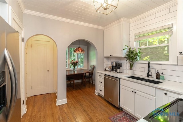 2448 Orchard Rd, Ottawa Hills, OH 43606 - kitchen with stainless steel appliances, arched walkways, decorative backsplash, ornamental molding, and light wood finished floors