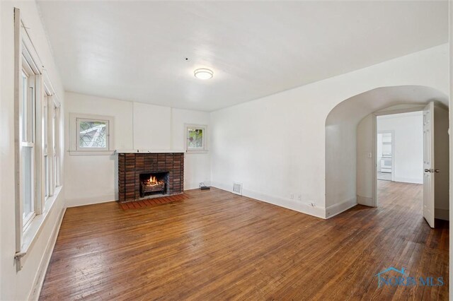 3042 Schneider Rd, Toledo, OH 43614 - unfurnished living room featuring wood-type flooring, a brick fireplace, and arched walkways