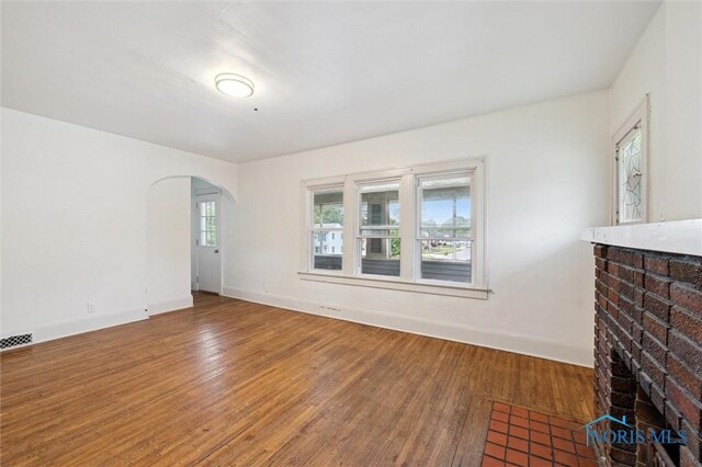 3042 Schneider Rd, Toledo, OH 43614 - unfurnished living room with hardwood / wood-style flooring, arched walkways, and a fireplace
