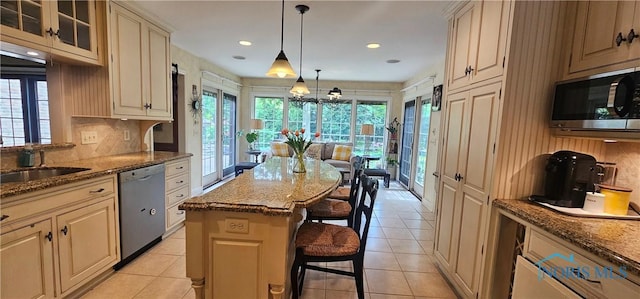 2720 Derby Rd, Ottawa Hills, OH 43615 - kitchen featuring stainless steel appliances, a kitchen bar, cream cabinets, dark stone counters, and tasteful backsplash