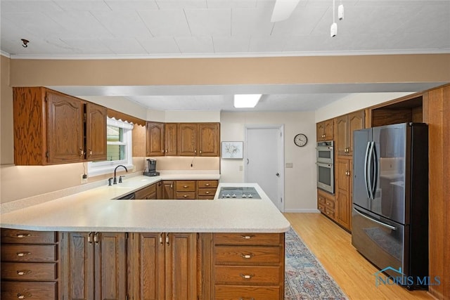 699 N Toussaint S Rd, Oak Harbor, OH 43449 - kitchen featuring stainless steel appliances, a peninsula, light countertops, light wood-style floors, and brown cabinetry