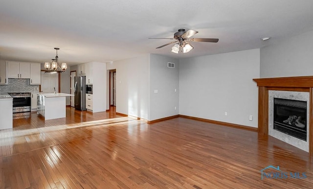 820 Weatherstone Rd, Holland, OH 43528 - unfurnished living room featuring a ceiling fan, a chandelier, light wood-style floors, and a tiled fireplace