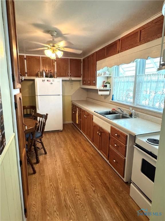 520 W Main St, Leipsic, OH 45856 - kitchen with white appliances, light countertops, a ceiling fan, light wood-style flooring, and brown cabinets