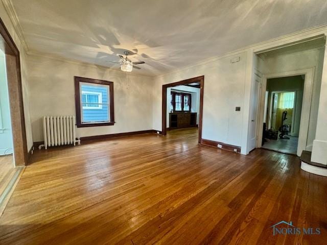 2840 Scottwood Ave, Toledo, OH 43610 - unfurnished living room featuring radiator, hardwood / wood-style floors, ceiling fan, crown molding, and healthy amount of natural light