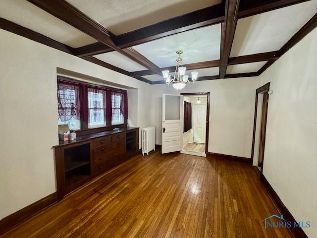 2840 Scottwood Ave, Toledo, OH 43610 - unfurnished living room with radiator, wood-type flooring, a chandelier, beamed ceiling, and coffered ceiling
