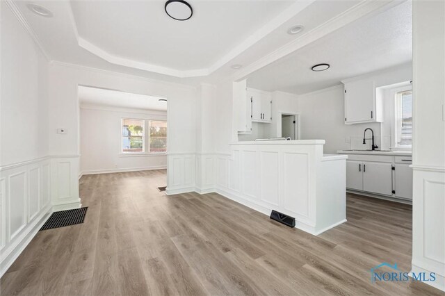 3627 Burton Ave, Toledo, OH 43612 - kitchen with a peninsula, light wood-type flooring, light countertops, white cabinetry, and wainscoting
