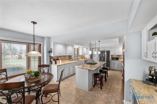 9627 Sheffield Rd, Perrysburg, OH 43551 - kitchen with appliances with stainless steel finishes, tasteful backsplash, a breakfast bar, a center island, and hanging light fixtures
