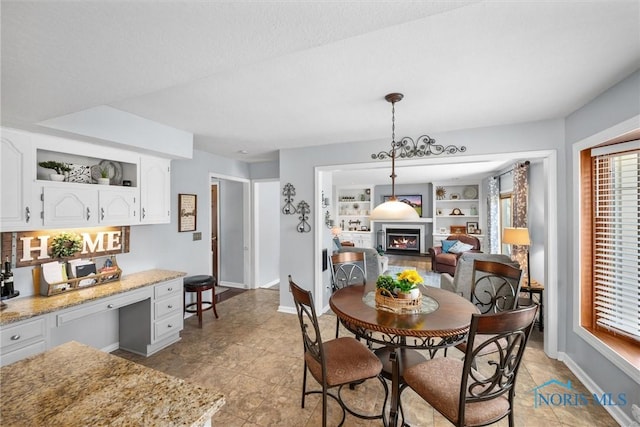 9627 Sheffield Rd, Perrysburg, OH 43551 - dining space featuring a lit fireplace, built in desk, and light tile patterned floors