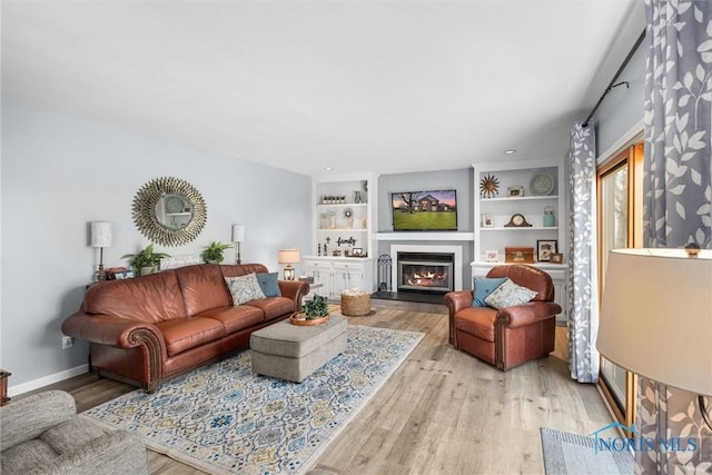 9627 Sheffield Rd, Perrysburg, OH 43551 - living room featuring light wood finished floors, a lit fireplace, and built in features