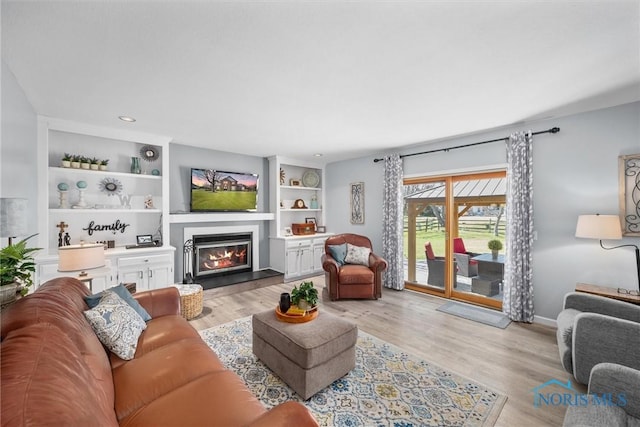 9627 Sheffield Rd, Perrysburg, OH 43551 - living area featuring light wood finished floors, a glass covered fireplace, built in features, and recessed lighting
