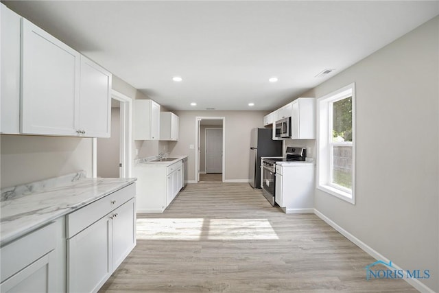 145 E Crocker St, Fostoria, OH 44830 - kitchen featuring appliances with stainless steel finishes, white cabinetry, light wood-type flooring, recessed lighting, and light stone counters