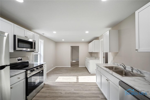 145 E Crocker St, Fostoria, OH 44830 - kitchen featuring stainless steel appliances, light wood finished floors, white cabinets, recessed lighting, and light stone countertops