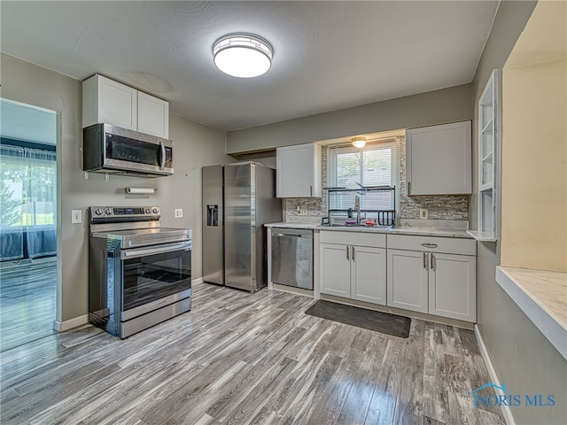 1323 Richland St, Maumee, OH 43537 - kitchen featuring appliances with stainless steel finishes, light wood-type flooring, tasteful backsplash, and white cabinets