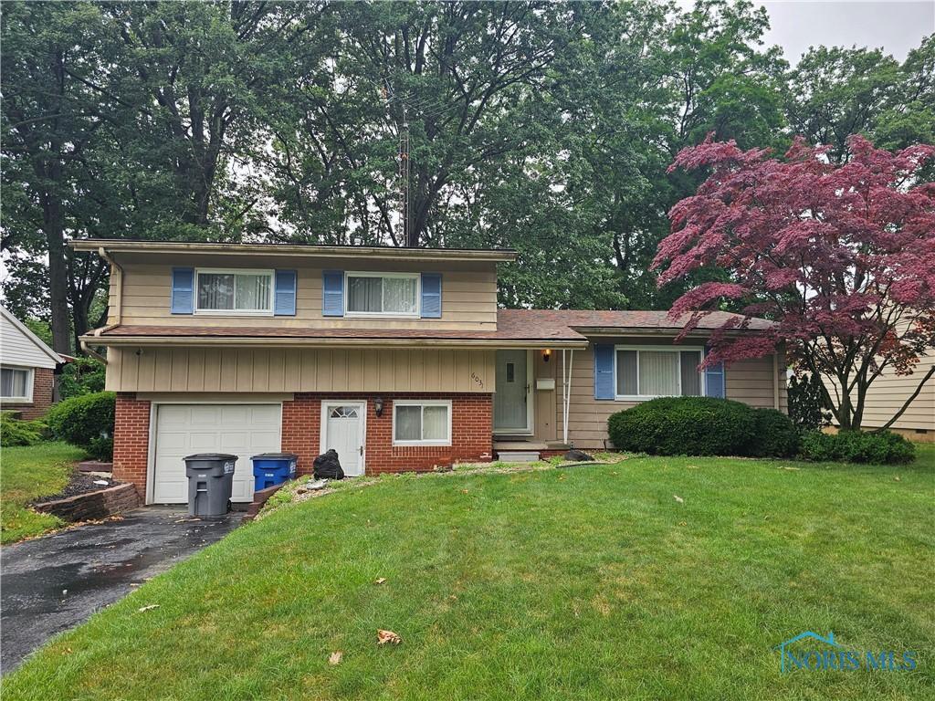 6031 Benalex Dr, Toledo, OH 43612 - tri-level home featuring a garage, driveway, a front lawn, and brick siding