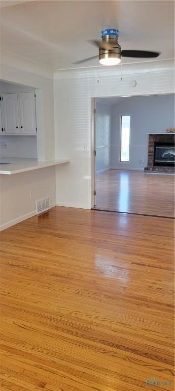 2550 Secor Rd, Toledo, OH 43606 - unfurnished living room with light wood-style flooring, ceiling fan, and a glass covered fireplace