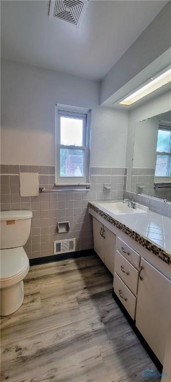 2550 Secor Rd, Toledo, OH 43606 - bathroom featuring tile walls, vanity, wood finished floors, and a wainscoted wall